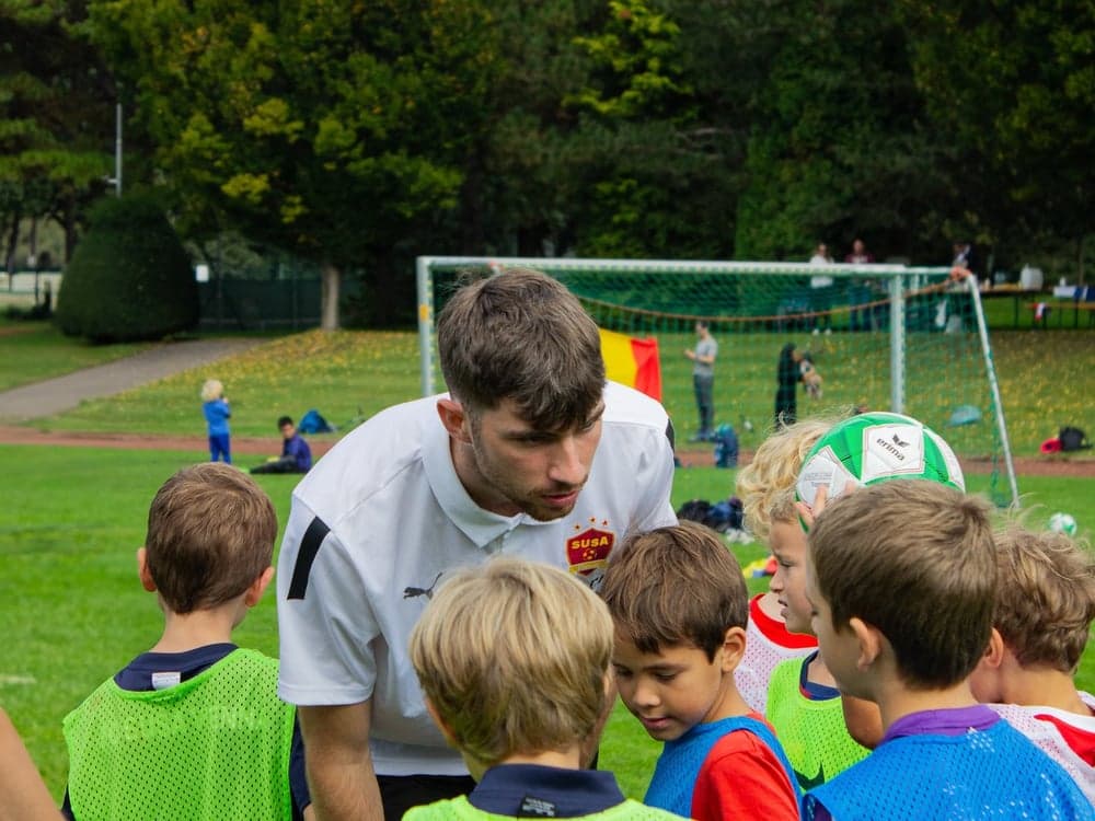 SUSA coach speaking to a group of boys in training pinnies