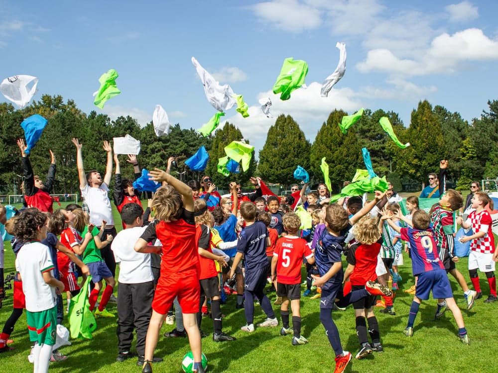 Children throwing colorful training bibs into the air