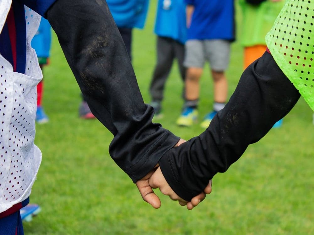 Two children holding hands on the pitch