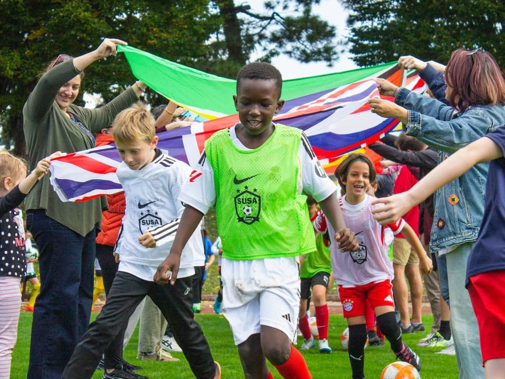 Kids playing with a parachute of flags at a SUSA camp
