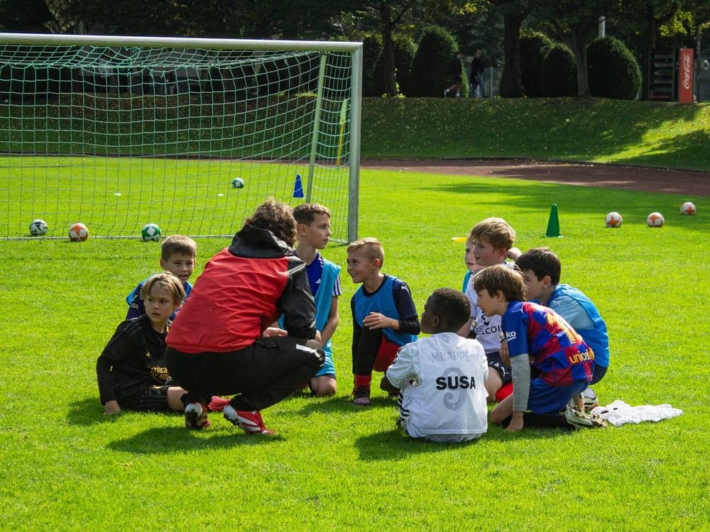 SUSA coach sitting in a circle talking with young players
